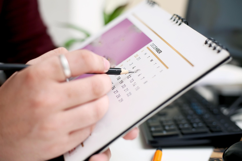 Hombre señalando con un lápiz una fecha del calendario de su oficina